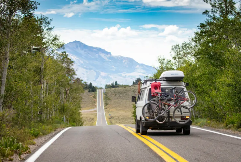 Why Mountain Towns Make the Perfect Weekend Getaway for Budget Travelers 7 Campervan On A Scenic Mountain Road With Bicycles Mounted On The Back, Perfect For Budget-Friendly Road Trips
