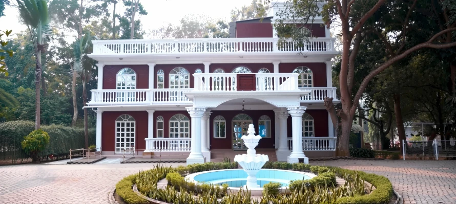 Best Resorts for Couples in Gazipur, Dhaka 20 Colonial-Style Red Villa With White Columns And Balconies At Angana Resort In Gazipur, Bangladesh, Surrounded By Trees And A Circular Fountain In The Front Courtyard.