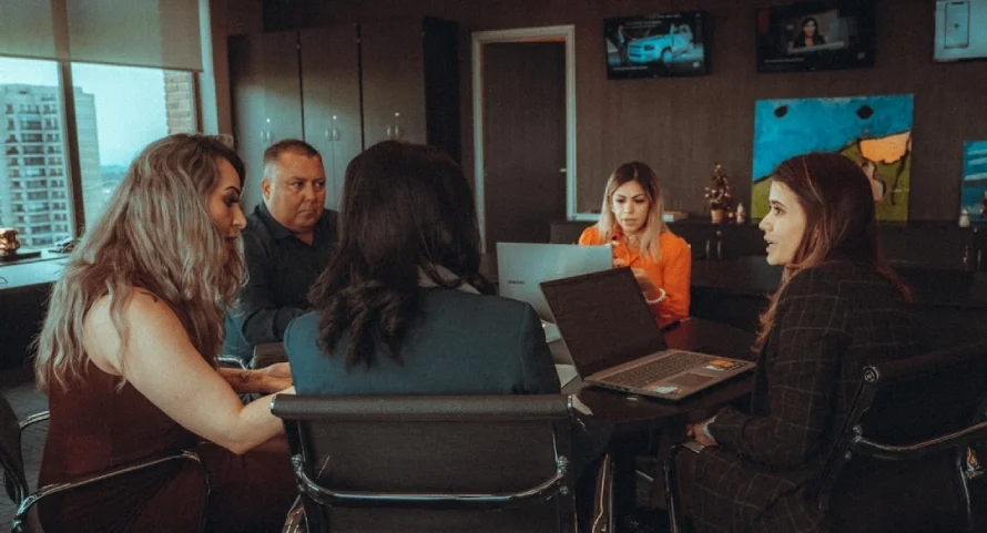 Understanding AI Integration: Transforming Business Processes for the Digital Age 2 A Group Of Professionals Collaborating At A Table, Using Laptops To Discuss Data-Driven Decision Making With Ai Analytics.